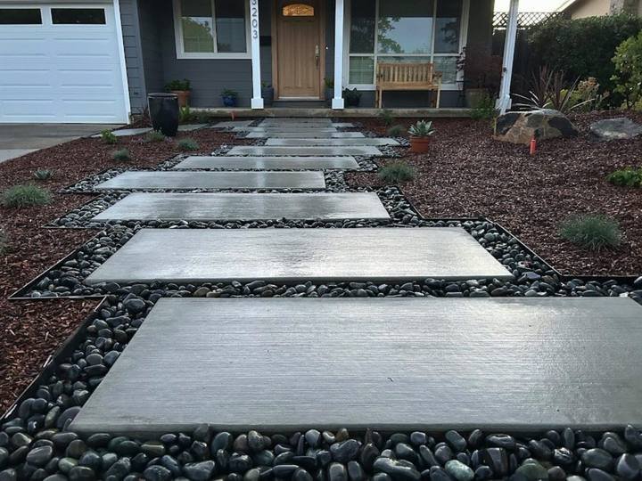 Oversized concrete stepping stones in river rock by DG Landscape Design